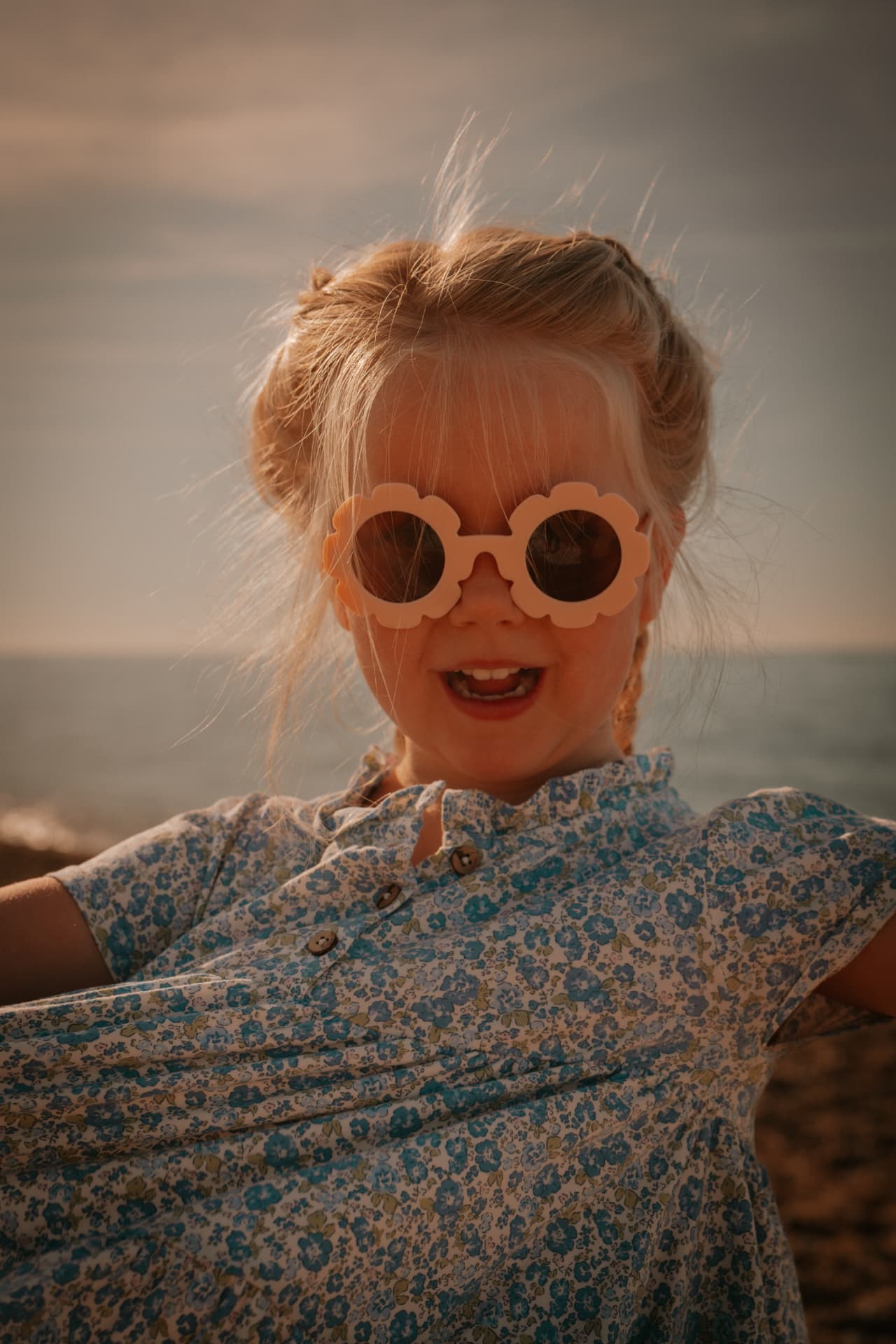 Meisje met zonnebril in het avondlicht aan zee